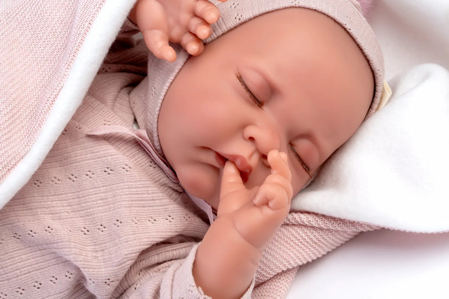 Muñeca Recién Nacida Luna de Antonio Juan, primer plano de la cara dormida con gorro rosa y mano en la boca