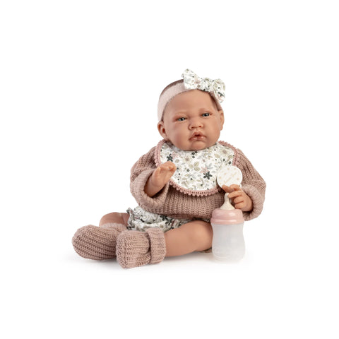Muñeca Recién Nacida Lúa de Antonio Juan sentada con jersey de punto, babero floral, chupete y biberón