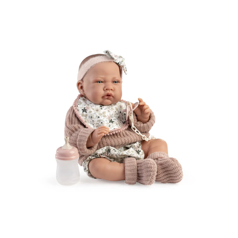 Muñeca Recién Nacida Lúa de Antonio Juan sentada con chaqueta rosa, babero de flores, chupete y biberón