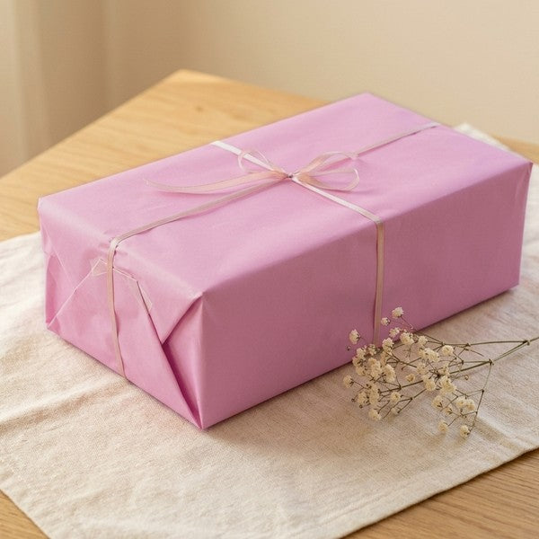 Caja de muñeca envuelta en papel rosa con lazo de raso